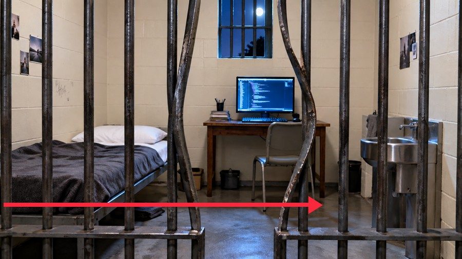 A prison cell with bent bars and a computer